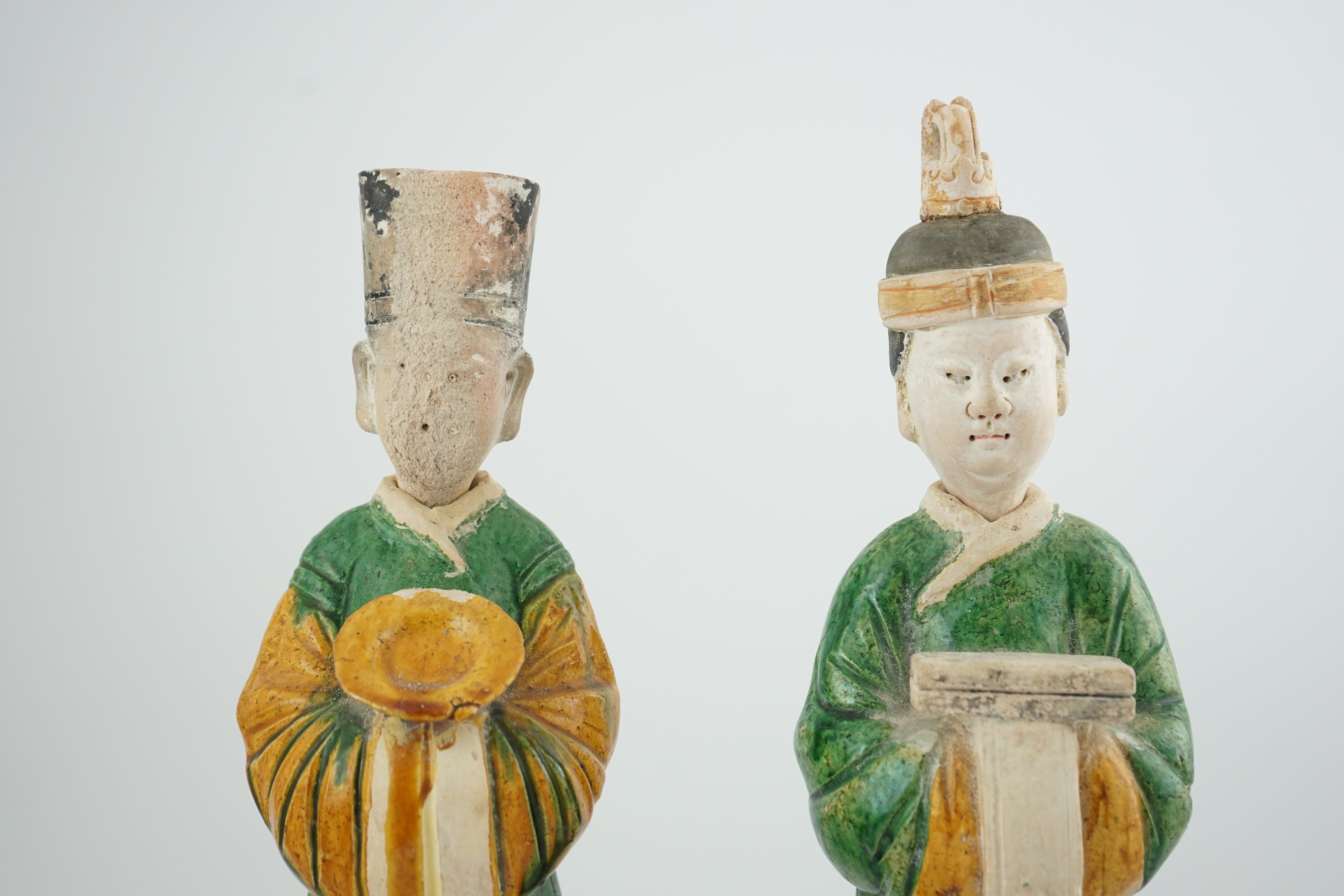 Two tall Chinese sancai figures of attendants, Ming dynasty, the male figure holding a dish and the female figure a box, each standing on a hexagonal base, largest 47cm high. Condition - some wear to face